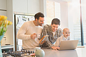 Male gay parents with baby son using tablet