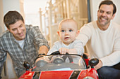Male gay parents pushing baby son in toy car
