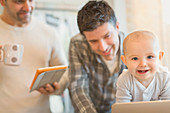 Baby son with male gay parents using tablet