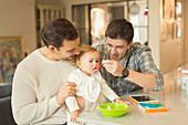 Male gay parents feeding baby son