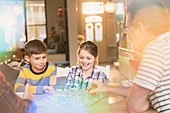 Father and children playing board game at table