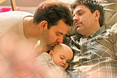 Affectionate male gay parents kissing baby son