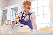 Smiling woman baking, icing layer cake