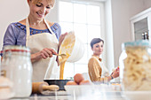 Female caterers pouring cake batter into tin