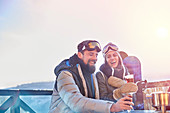 Snowboarder couple laughing, drinking cocktails