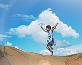 Exuberant girl jumping on beach hill