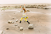 Exuberant girl jumping for joy on beach rocks