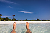 Barefoot man floating surf with view of beach