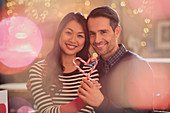 Portrait couple holding heart-shape candy canes