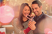Couple holding heart-shape candy canes