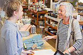 Smiling female shopper and cashier talking