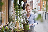 Smiling female florist holding potted plant
