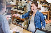 Pregnant woman giving basket to cashier