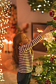 Girl hanging ornament on Christmas tree