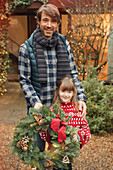 Smiling father and daughter with Christmas wreath