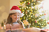 Girl in Santa hat holding snowflake ornament