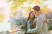 Young couple with bicycle on bridge over canal