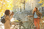 Young woman photographing friend with bicycle