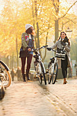 Young women friends walking bicycles