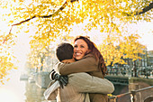 Happy couple hugging along autumn canal