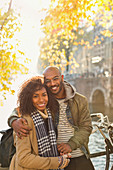 Portrait couple hugging along autumn canal