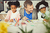 Father and daughters colouring with markers
