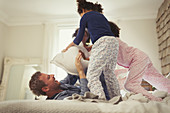 Father and daughters pillow fighting on bed