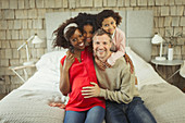 Portrait pregnant young family hugging on bed