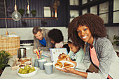 Mother eating breakfast toast with young family