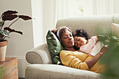 Serene mother and daughter cuddling on sofa