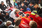 Manager and pit crew around formula one driver