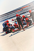 Pit crew replacing tires on formula one race car