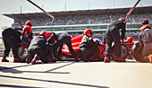 Pit crew replacing tires on formula one race car