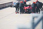 Pit crew pushing race car out of pit lane