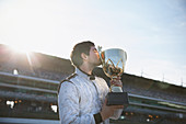 Male formula one driver kissing trophy