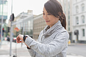Smiling female runner checking wristwatch