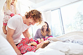 Family laughing and playing on bed