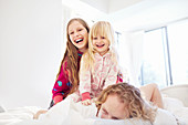 Laughing sisters on top of father on bed