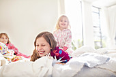 Laughing sisters playing on bed