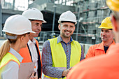 Smiling engineers and construction workers meeting
