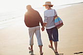 Barefoot mature couple holding hands and walking