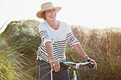 Smiling mature woman riding bicycle grass path