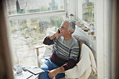 Senior man talking on cell phone on sun porch