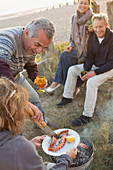Mature couples barbecuing on beach