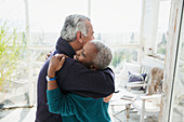 Affectionate senior couple hugging on sun porch