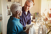 Senior couple talking and doing dishes in kitchen