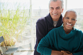 Portrait senior couple hugging on sun porch