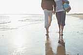 Barefoot mature couple walking, holding hands