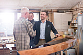 Male carpenters handshaking with customer