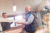 Portrait senior male carpenter lifting wood boat